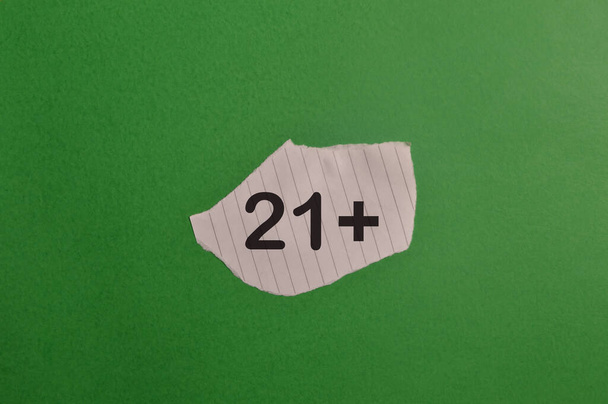 Papel desgarrado con signo 21 plus aislado sobre fondo verde - Foto, Imagen