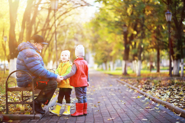 Dzieci z dziadkiem na spacerze w jesiennym parku  - Zdjęcie, obraz
