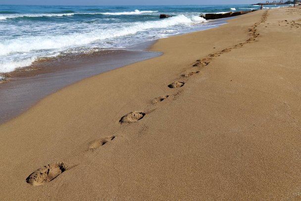 Lábnyomok a homokban a Földközi-tenger partján, Észak-Izraelben. Meleg nyár Izraelben.  - Fotó, kép