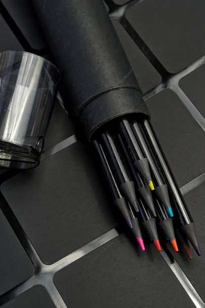 Ensemble de crayons de couleur dans un étui rond en carton sur fond sombre - Photo, image