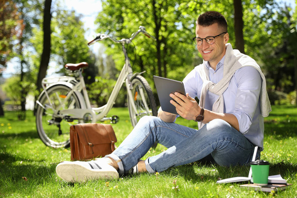 Man working with tablet on grass in park - Zdjęcie, obraz