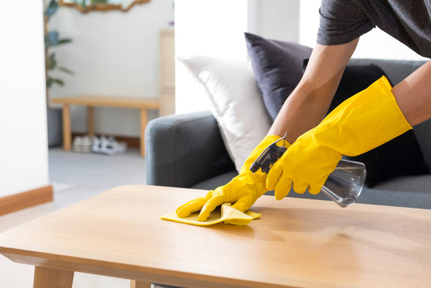 Sanitising surfaces cleaning home table with disinfectant spray with towel and gloves. COVID-19 prevention. - Photo, image