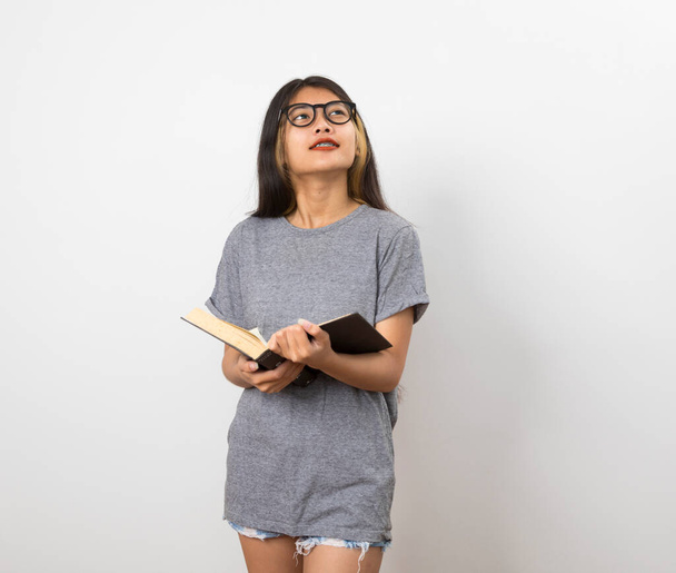 Młoda piękna Azjatka trzyma książkę podczas myślenia - Zdjęcie, obraz