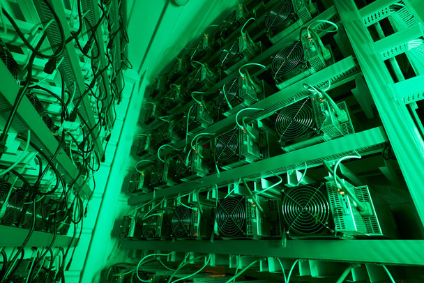 Bitcoin miners in large farm. ASIC mining equipment on stand racks mine cryptocurrency in steel container. Blockchain techology application specific integrated circuit datacenter. Server room lights. - Photo, image