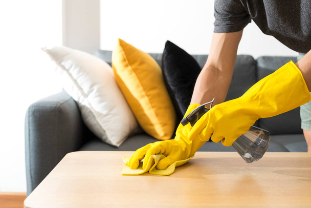 Ev masasını dezenfektan spreyle temizleme havluyla ve eldivenle. COVID-19 önleme. - Fotoğraf, Görsel