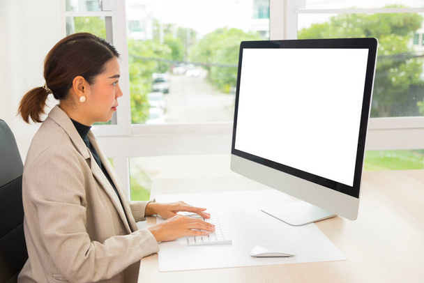 成熟したアジアの女性がオフィスで働き,コンピュータ画面を見る. - 写真・画像