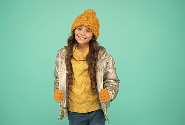 smiling teenage girl in padded or puffer jacket ready to spent winter holiday and vacation in comfort and warmth, knitted fashion - Foto, afbeelding