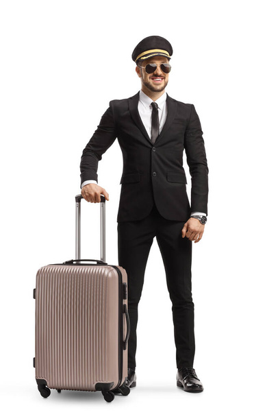 Full length portrait of a man in a suit and tie with sunglasses and a cap carrying a suitcase isolated on white background - Foto, Imagen