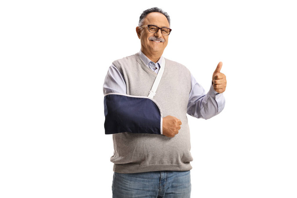 Mature man with an arm splint smiling at camera and gesturing a thumb up sign isolated on white background - Fotografie, Obrázek