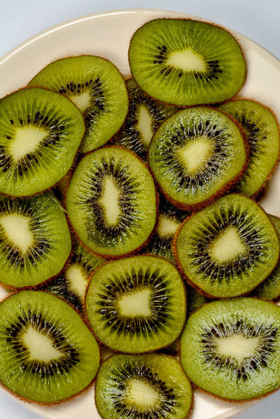 Plate of fresh kiwi fruits with the cross-sections on wooden table with copy space.Kiwi on a plate. - Photo, Image