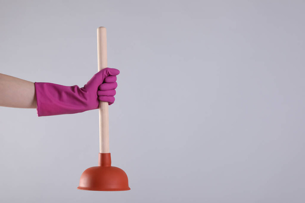 Woman holding plunger on light grey background, closeup. Space for text - Foto, immagini