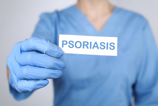 Doctor holding card with word PSORIASIS on light grey background, closeup - Φωτογραφία, εικόνα