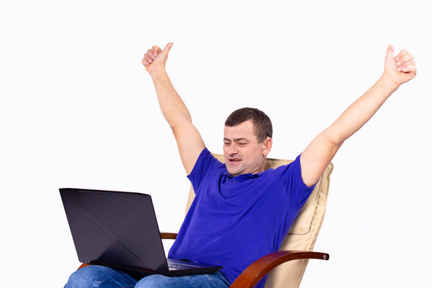 Happy man with hearing aid and hands up is talking online sitting in the chair with computer the knees. High quality photo - Фото, зображення