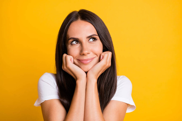 Photo of young attractive woman happy positive smile dream look empty space hands touch cheeks isolated over yellow color background - Фото, изображение
