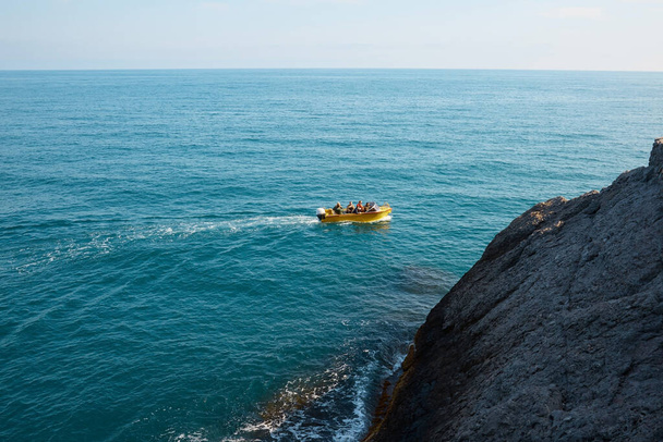 barca con passeggeri in mare, vacanze estive, gita in barca in mezzo a rocce e montagne, paesaggio marino - Foto, immagini