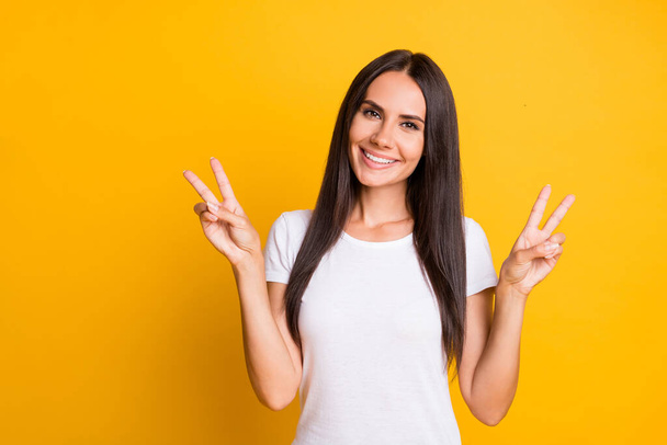 Photo of young attractive woman happy positive smile show peace cool v-sign isolated over yellow color background - Фото, изображение