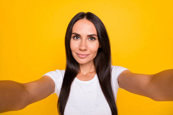 Photo portrait of brunette blogger taking selfie smiling in white t-shirt isolated on vibrant yellow color background - Fotoğraf, Görsel