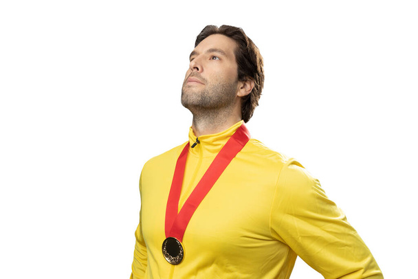 male athlete smiling after winning a gold medal in a white background. Sportsman with medal celebrating his victory. - Photo, Image