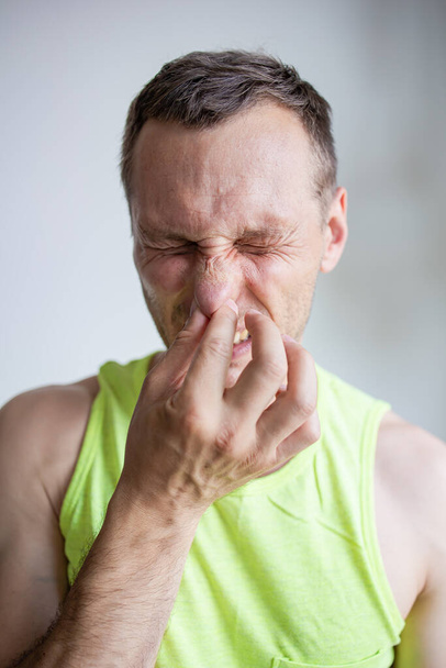 Ο άνθρωπος τσιμπάει τη μύτη φαίνεται με αηδιαστική Κάτι βρωμάει κακή μυρωδιά - Φωτογραφία, εικόνα