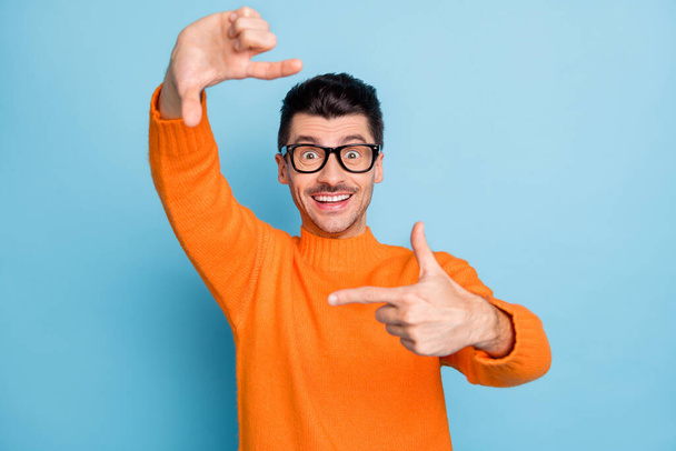 Photo of positive young man hands fingers show cadre toothy smile wear sweater isolated on blue color background - Fotografie, Obrázek