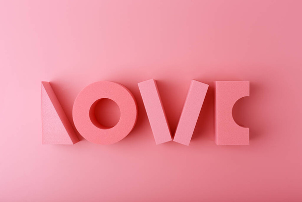 明るいピンクの背景にピンクのおもちゃの幾何学的な数字で作られた言葉の愛と創造的なフラットレイ。愛、関係、バレンタインデー、母の日、または団結の概念 - 写真・画像
