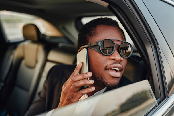 Successful african businessman with phone inside of car - Zdjęcie, obraz