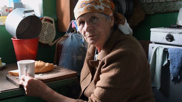 Πορτρέτο της θλιμμένης ζαρωμένης γυναίκας που παίρνει πρωινό στη ρουστίκ κουζίνα στη μοναξιά - Φωτογραφία, εικόνα