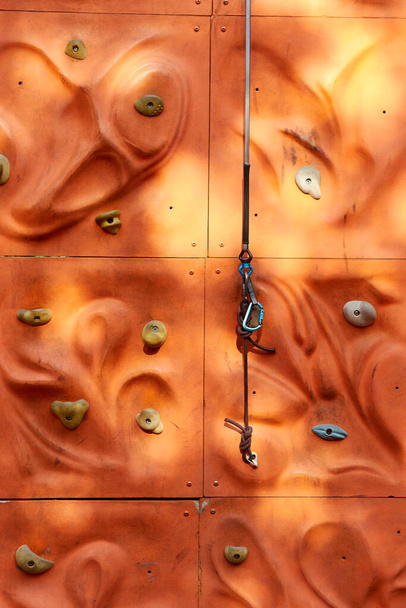 fragment of climbing wall with rope and snap hook for beginners in public park.  - Photo, Image