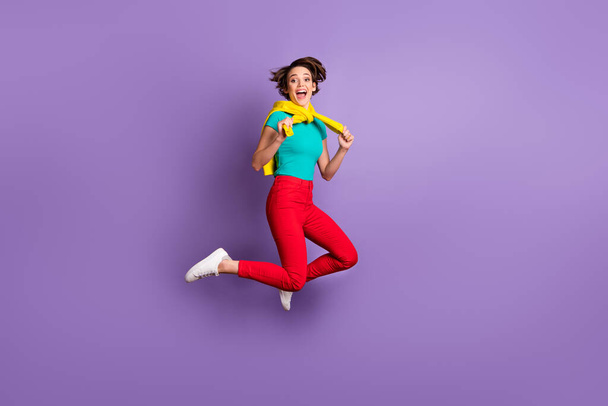 Full length photo of lady jump open mouth wear tied pullover t-shirt trousers sneakers isolated purple color background - Φωτογραφία, εικόνα