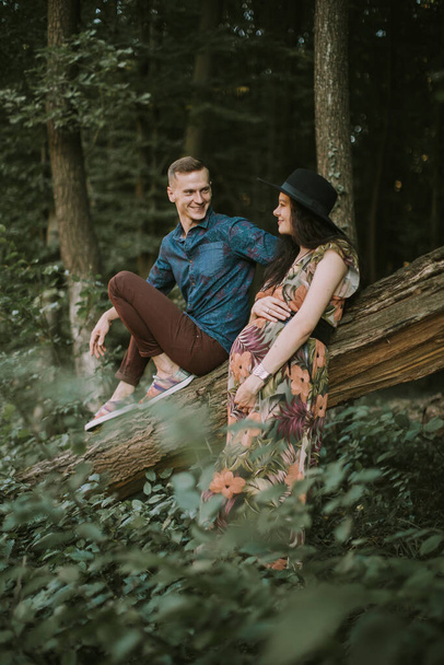 Pregnant girl with big cute belly and young man in beautiful forest - Zdjęcie, obraz