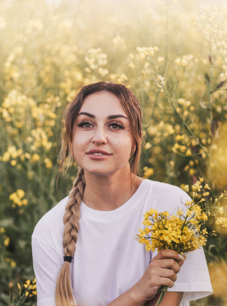 Feliz joven mujer caminando en el campo amarillo en el día de verano - Foto, Imagen