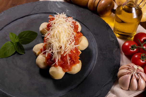 Gnocchi με φυσική βιολογική σάλτσα ντομάτας χωρίς φυτοφάρμακα με τριμμένο τυρί παρμεζάνα και φύλλα βασιλικού.. - Φωτογραφία, εικόνα