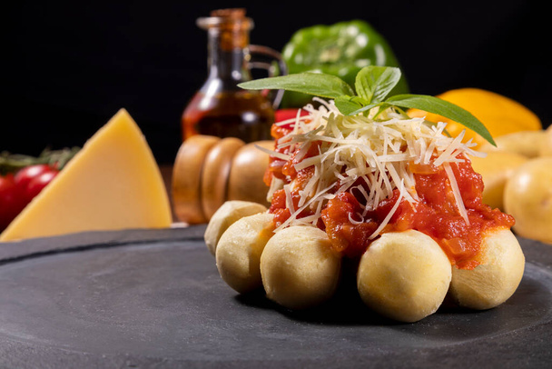Gnocchi met natuurlijke biologische tomatensaus zonder pesticiden met geraspte Parmezaanse kaas en basilicumbladeren. - Foto, afbeelding