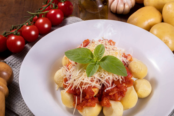 Gnocchi természetes organikus paradicsommártással, peszticidek nélkül reszelt parmezán sajttal és bazsalikomlevéllel.. - Fotó, kép