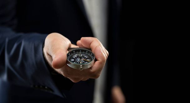 Businessman holding a navigation compass in his hand. Business planning and business navigation for recovery so that businessmen resume business growth amid the economic crisis. - Foto, Imagen