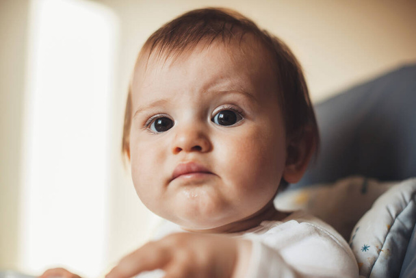 Close up photo of a baby girl doing something at home while sitting on the couch - Foto, imagen