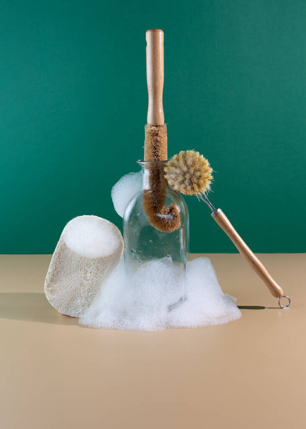 Reusable wooden dish washing brush with coconut bristle on a beige background with soapy foam. Place for your text. Cleaning concept. Cleaning service. Zero waste and low-waste living - Photo, Image