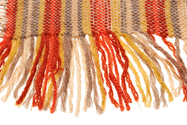 kis, kézzel készített szőnyeg vagy lábtörlő peremén, vörös és sárga gyapjúszálakból szőve, egy tárgy közelkép - Fotó, kép