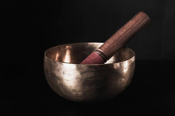 A Tibetan singing bowl with a stylus inside. Dark background. - Valokuva, kuva