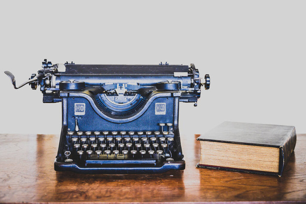 máquina de escrever preto antigo com livro velho sobre mesa de madeira de mogno visto de perto - Foto, Imagem