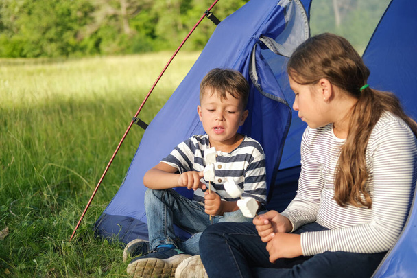 İki çocuk çadırda oturup lokum yiyor. - Fotoğraf, Görsel