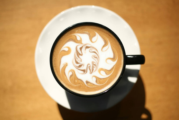 Λάτε. Λατ Αρτ. Latte art με ζεστό καφέ latte. Αφρός γάλακτος σε σχέδιο φύλλων πάνω από την τέχνη του latte από επαγγελματία barista καλλιτέχνη. Καφές Λατ Αρτ. Οι καφετέριες. Ζεστός καφές σε ένα φλιτζάνι στο τραπέζι. Ζεστή σοκολάτα latte τέχνη στο τραπέζι. - Φωτογραφία, εικόνα