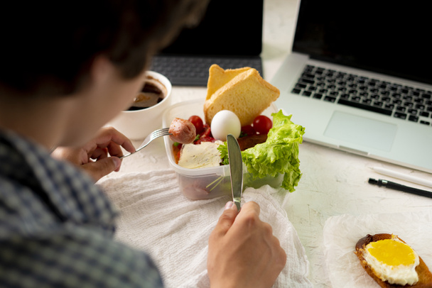 молодий чоловік приймає їжу перед ноутбуком під час роботи, погану звичку та концепції ожиріння
 - Фото, зображення