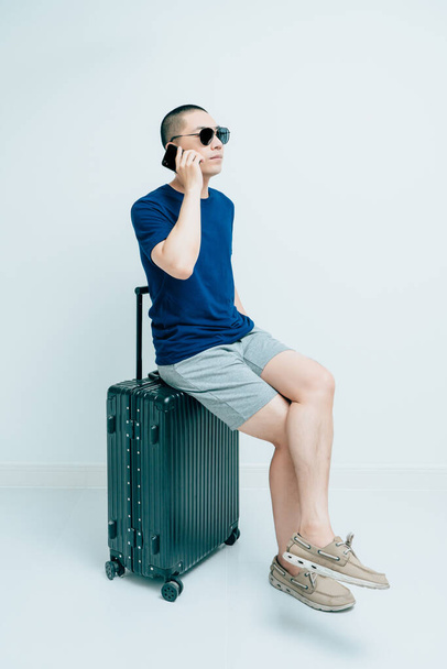 Junger Mann sitzt auf schwarzem Koffer und ruft - Foto, Bild