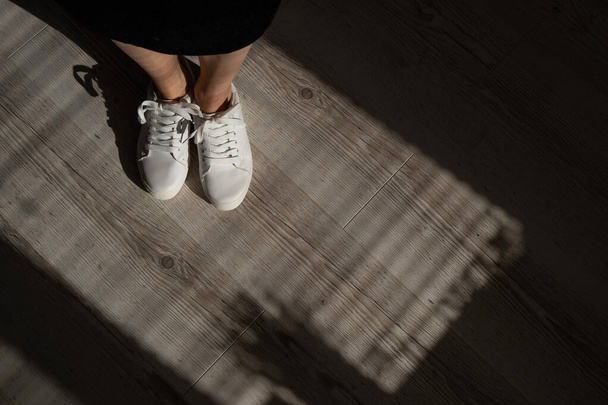 Close-up of female legs in white leather sneakers. - Foto, afbeelding