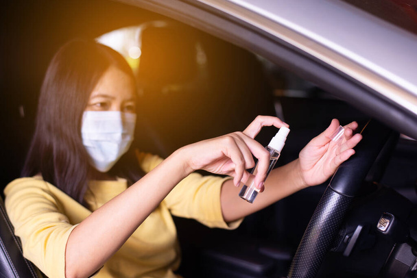Frau benutzt Händedesinfektionsspray vor dem Autofahren, Vorsorgemaßnahmen gegen Coronavirus, Covid-19-Pandemie - Foto, Bild