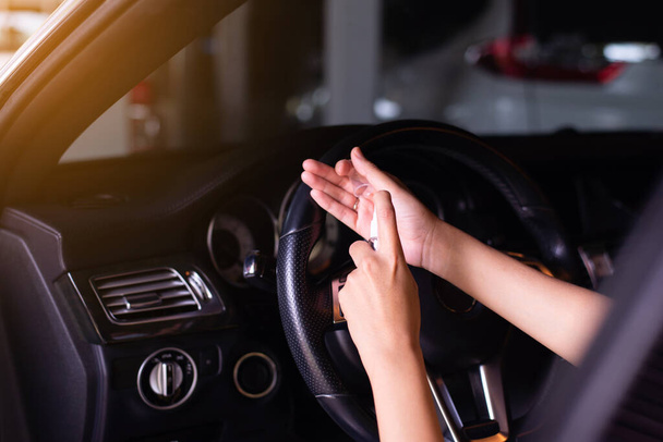 Woman using hand sanitizer spray before driving a car,Preventive measures against coronavirus,Covid-19 pandemic - Фото, зображення