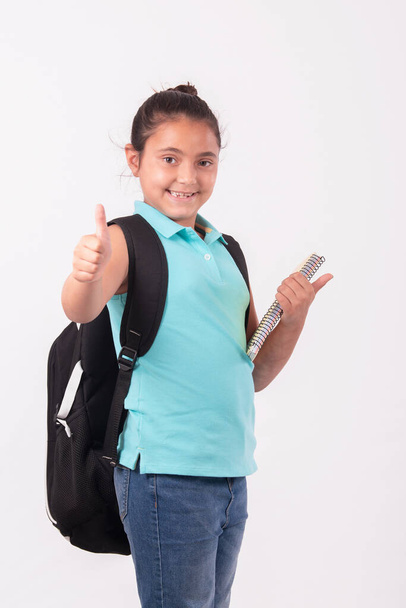 Pequeña chica latina haciendo un gesto de pulgar hacia arriba llevando una gran mochila: Concepto escolar. - Foto, imagen