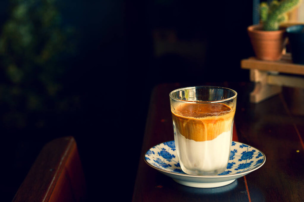 A cup of strong coffee with milk is placed on the table in the morning. - Photo, Image