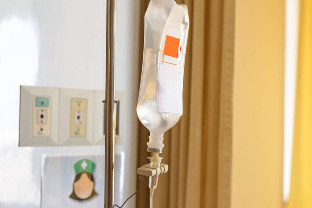 zblízka fyziologického roztoku sáček visí na stanovišti pro pacienta ležícího na nemocničním lůžku, kapka fyziologického roztoku na pomoc pacientovi - Fotografie, Obrázek